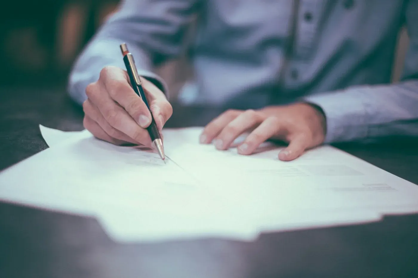 Hands reviewing and signing paperwork — illustrative budget planning photograph